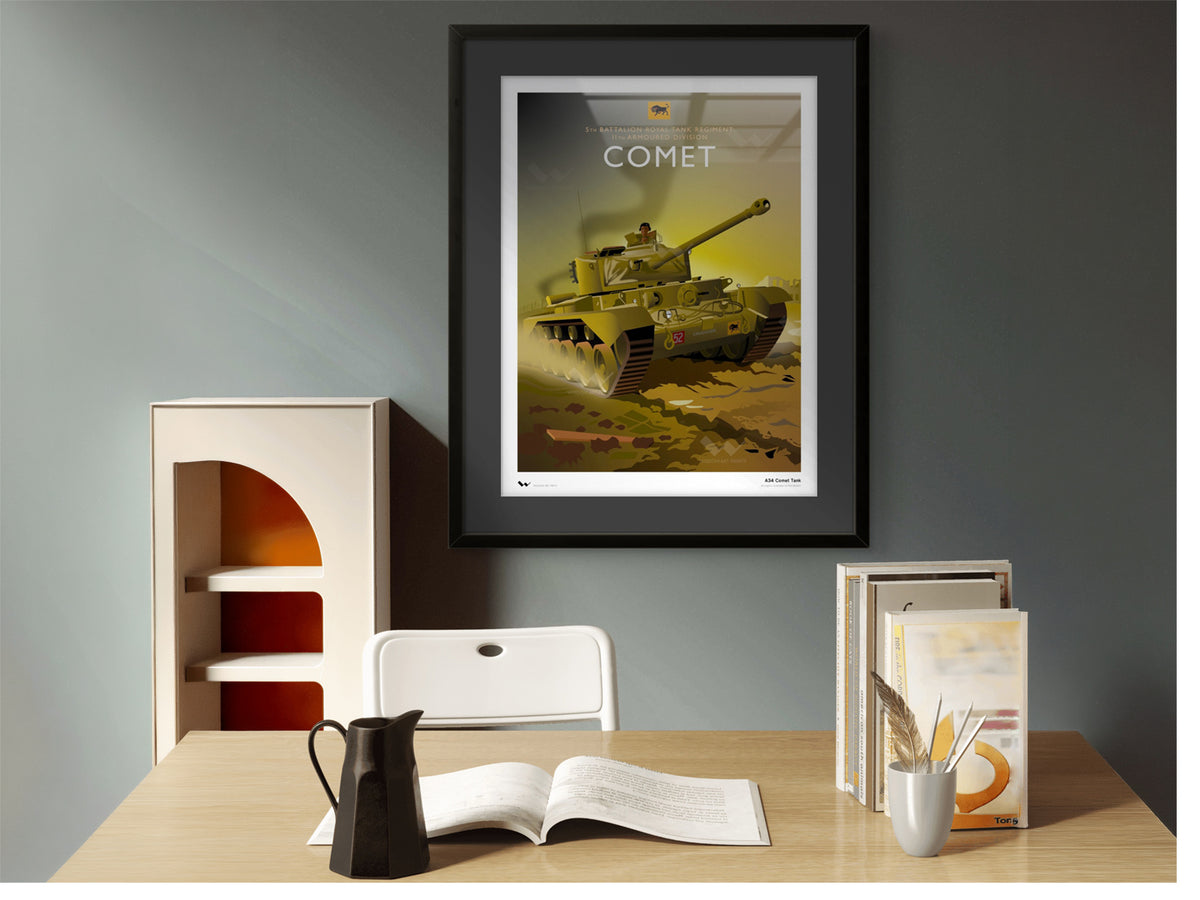 A framed art print of a military tank labeled 'COMET' hanging on a gray wall above a wooden desk with books, a chair, and a coffee pot.