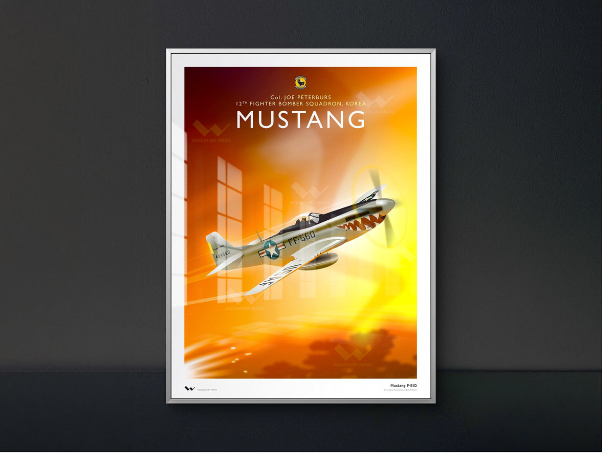 A framed vintage-style art print featuring a silver Mustang fighter plane flying over an orange and yellow sunset, displayed against a dark gray wall.